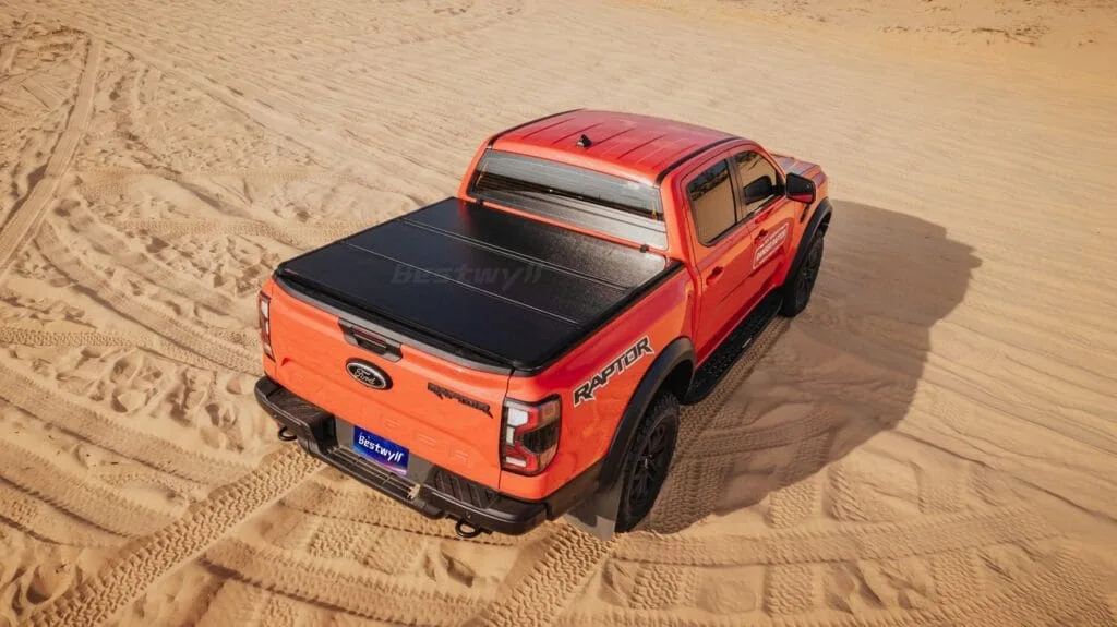 Pickup truck with tri-fold cover driving in desert terrain